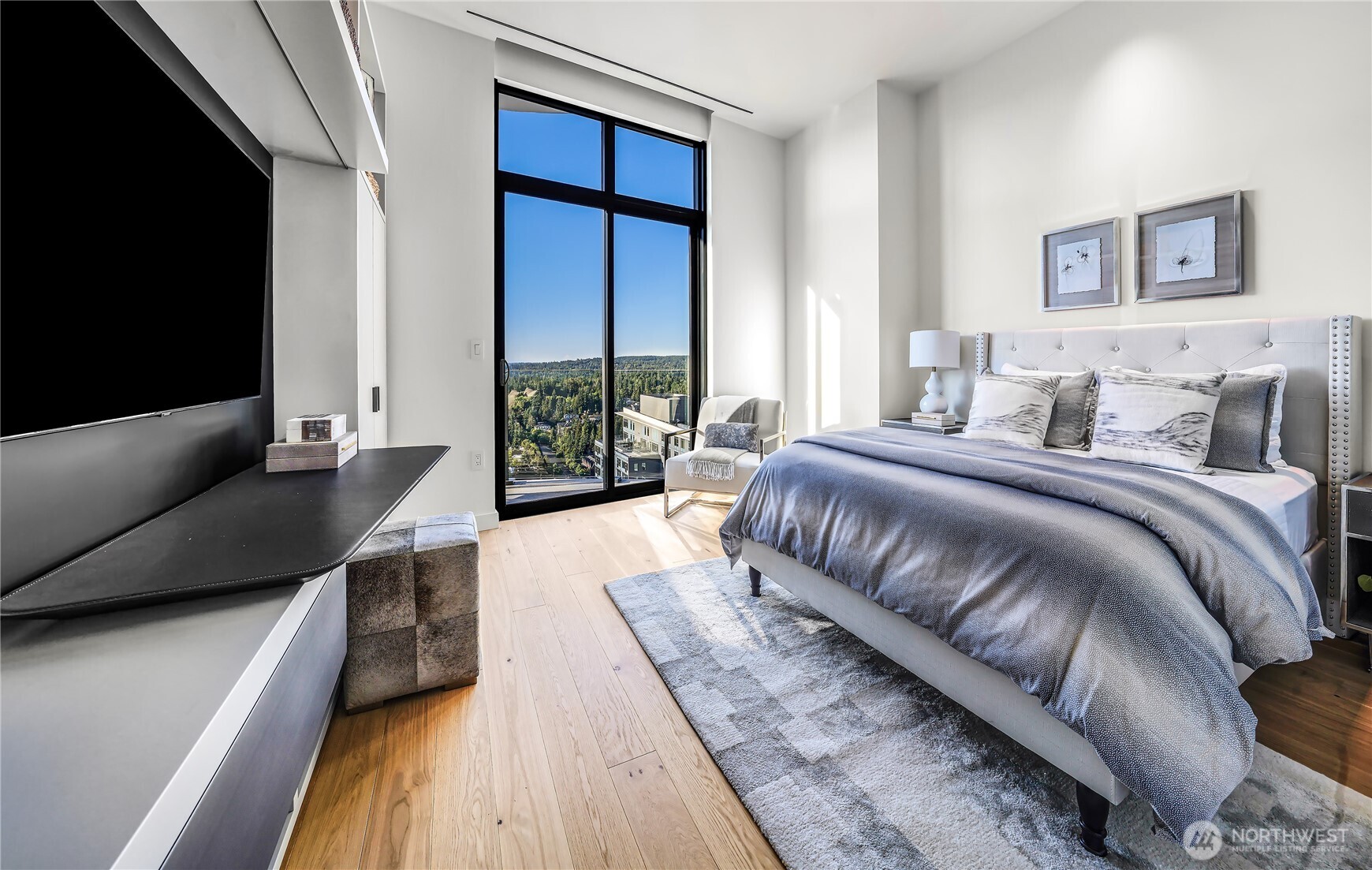 Furnished bedroom with a king bed and floor-to-ceiling windows overlooking green hills.