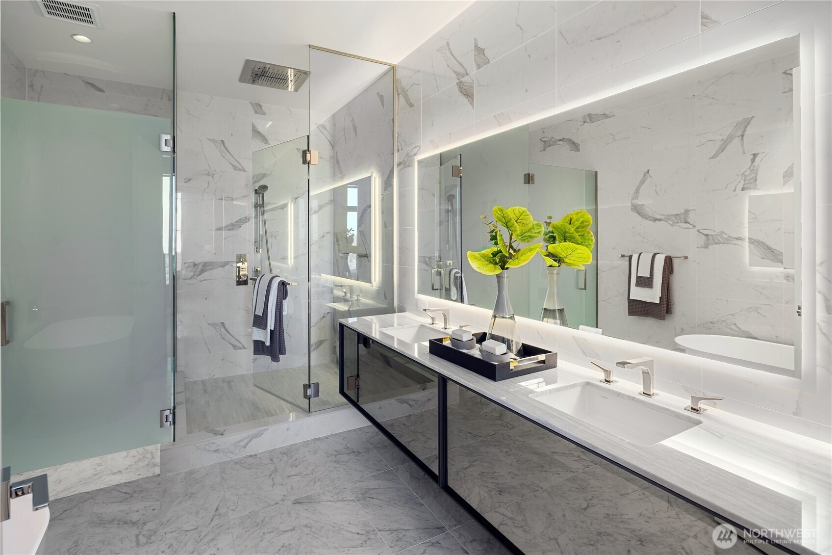 Marble bathroom with a glass shower, double vanity, and illuminated mirrors.