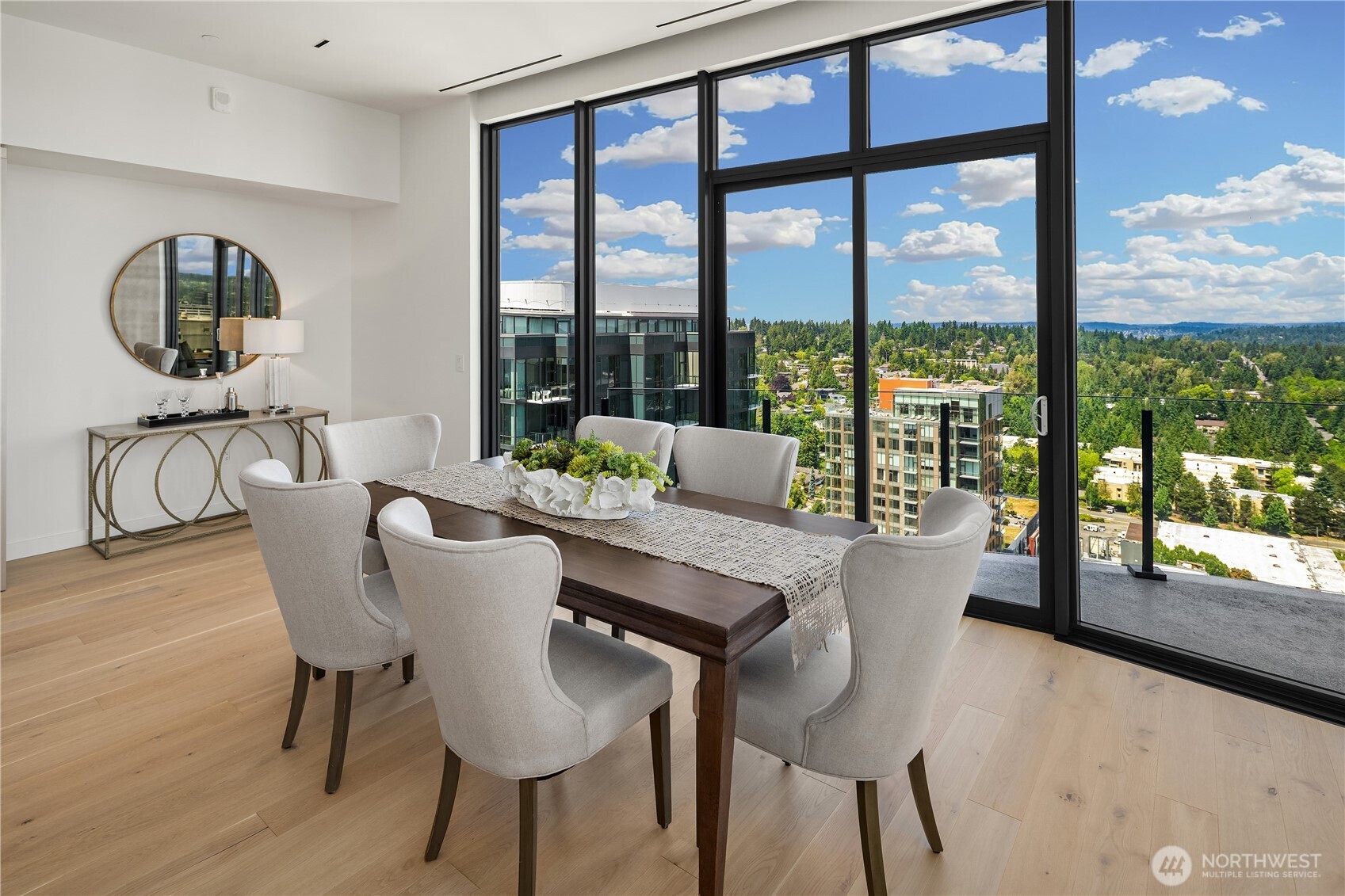 Dining room with floor-to-ceiling windows overlooking Bellevue’s buildings and green neighborhoods.