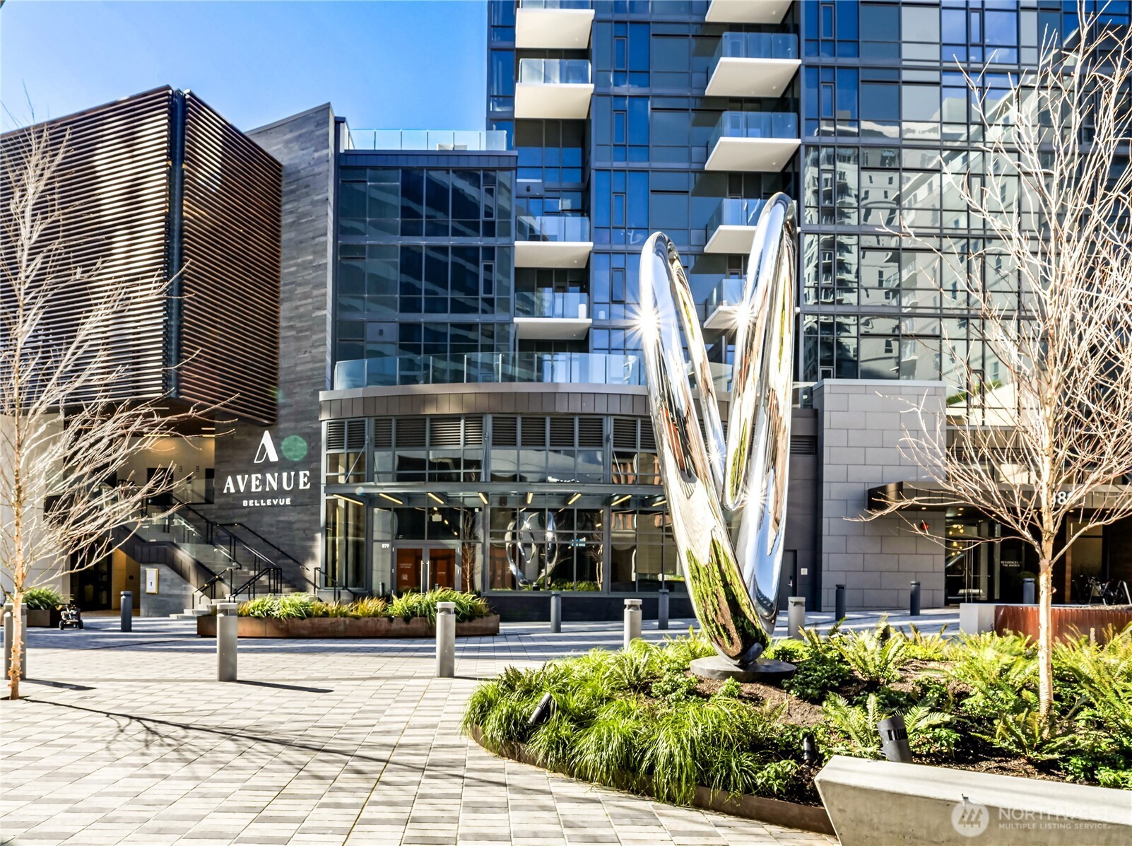Avenue Bellevue condominium exterior with glass balconies and a polished metal sculpture in the plaza.