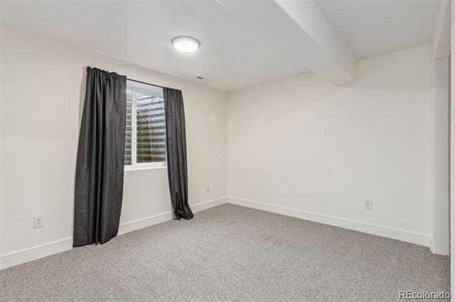 Empty carpeted bedroom with a window framed by dark curtains.