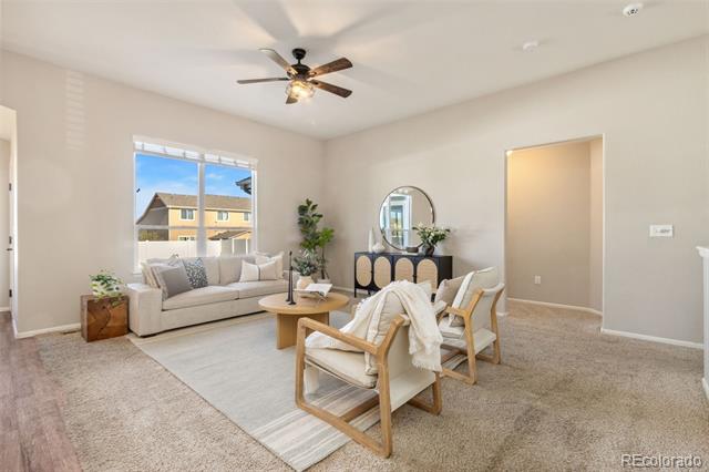 Staged living room with a light sofa, two armchairs, a round coffee table, and a large window.