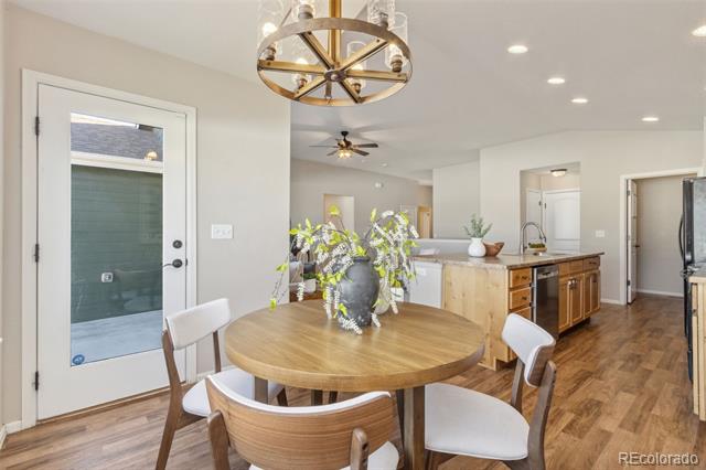 Dining area with a round wood table and chandelier beside an open kitchen.