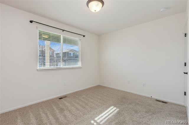 Empty carpeted room with a window and horizontal blinds.
