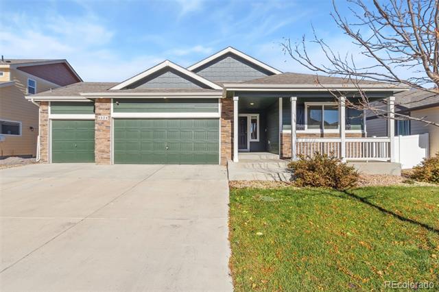 Front exterior of a gray home with green garage doors, a wide driveway, and a covered porch.