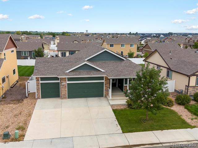 Single-story home with a dark green double garage door, wide driveway, and front lawn.