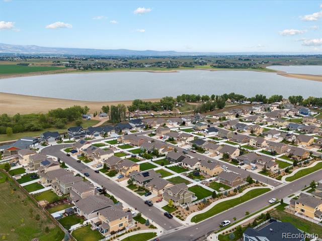 Aerial view of a residential neighborhood beside a broad reservoir, with distant mountains and farmland.