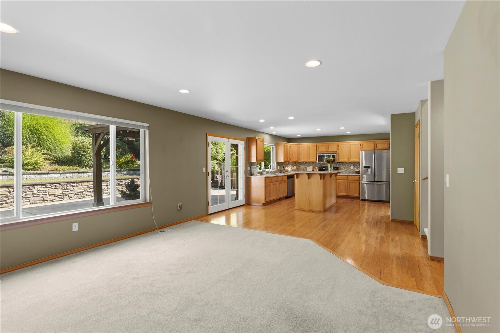 Open living area and kitchen with a central island, wood cabinetry, and sliding doors to the garden.