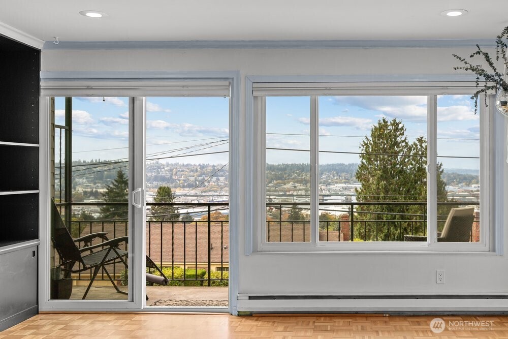 Bright room with broad windows and a sliding door opening onto a balcony with neighborhood views.