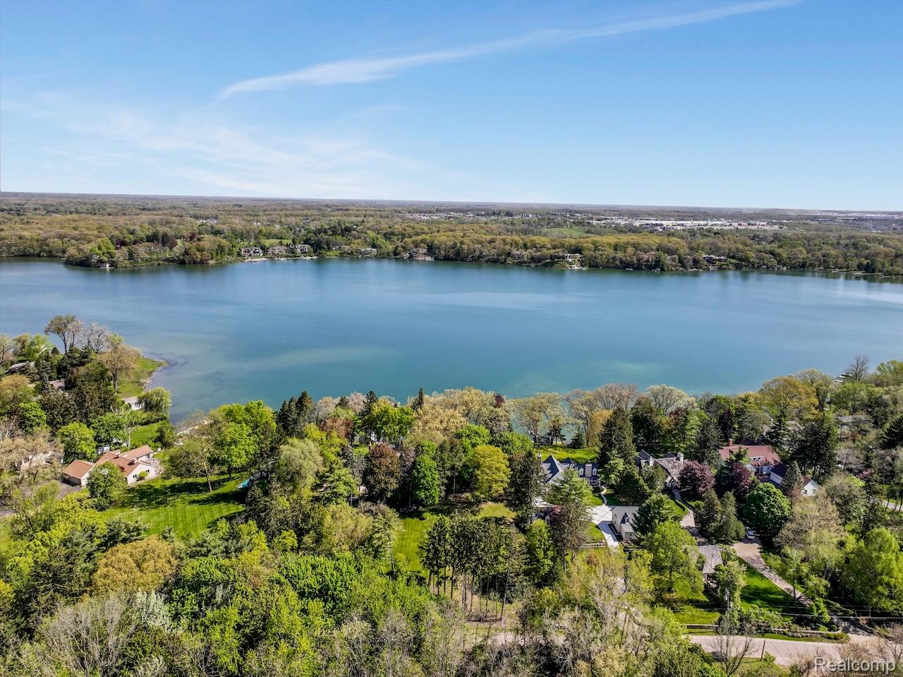 Aerial view of Lake Angelus and wooded shoreline homes on a clear spring day.