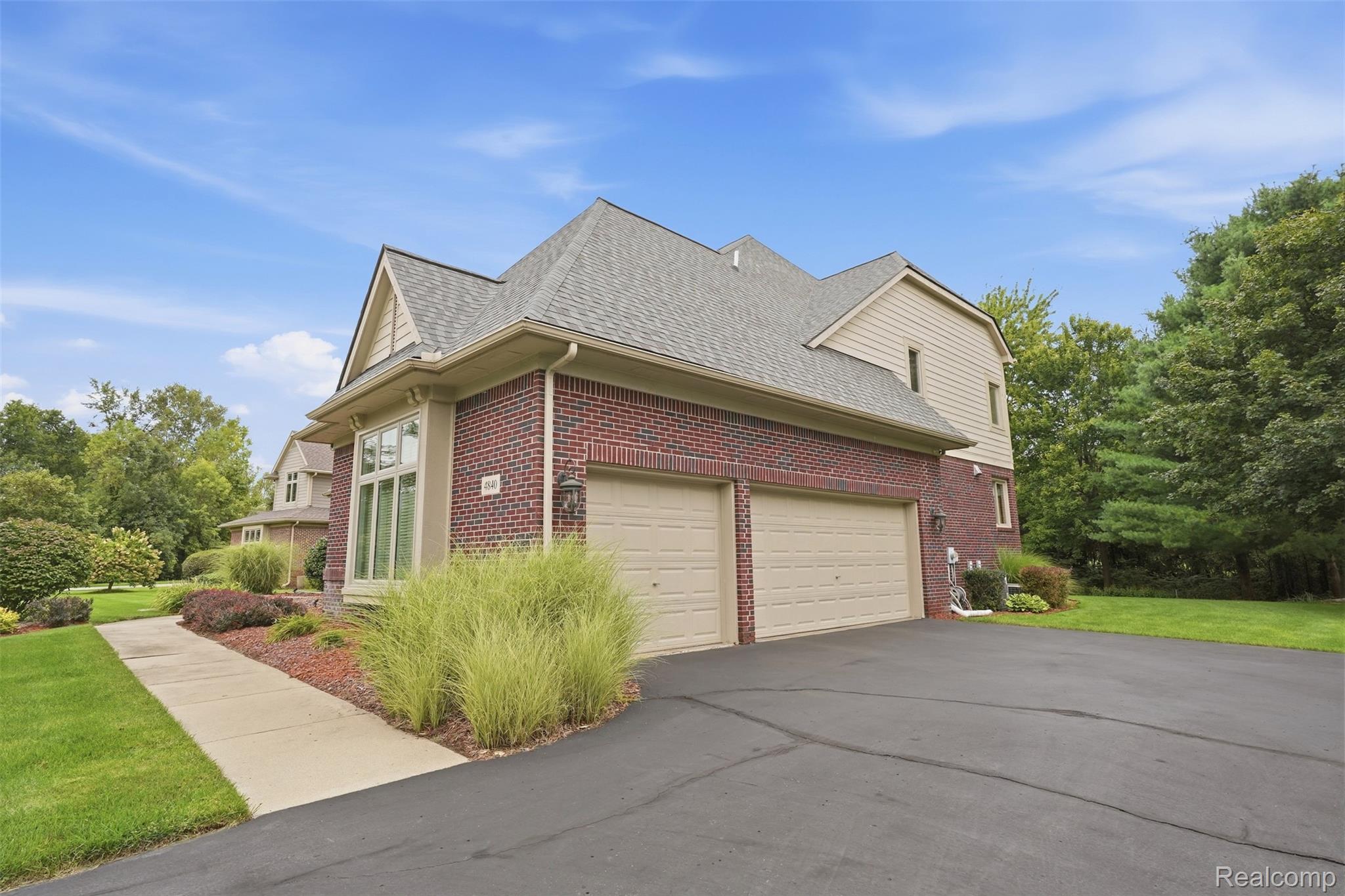 Two-story brick-and-siding house with a steep roof, double garage, wide driveway, and landscaped front yard.