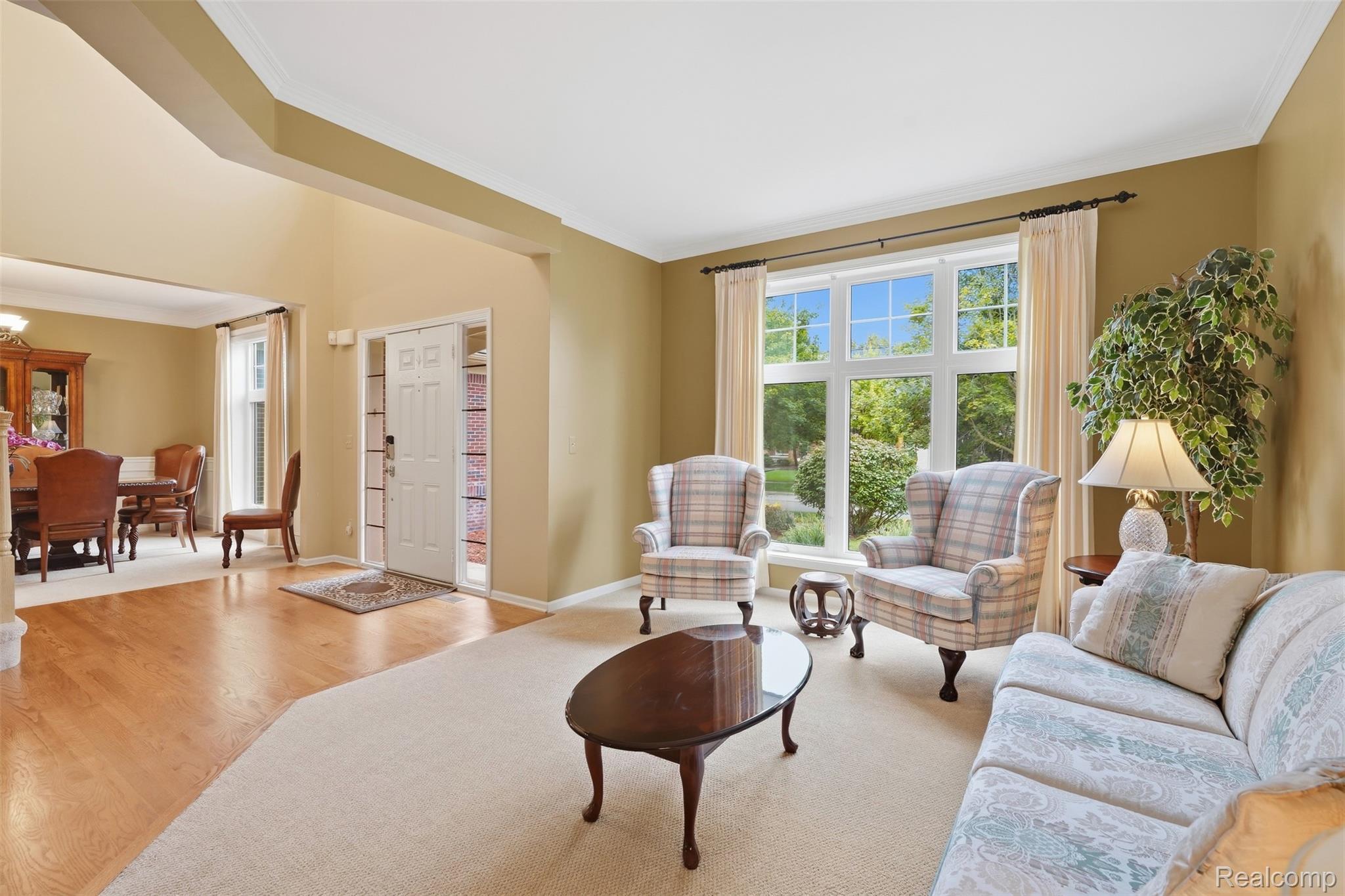 Living room with plaid armchairs, a large garden-facing window, and an adjoining dining area.