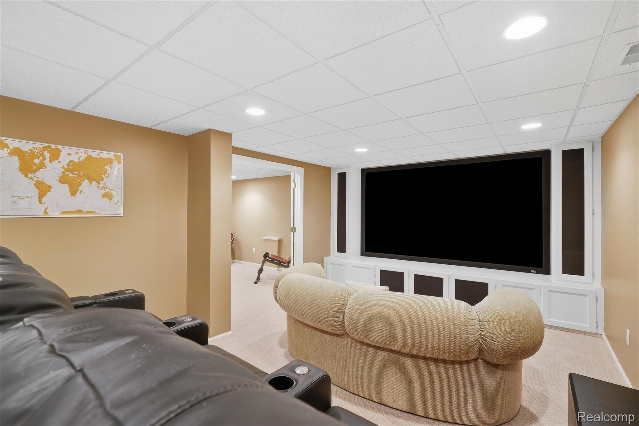 Home theater with a large screen, built-in cabinetry, leather recliners, and a rounded upholstered sofa.