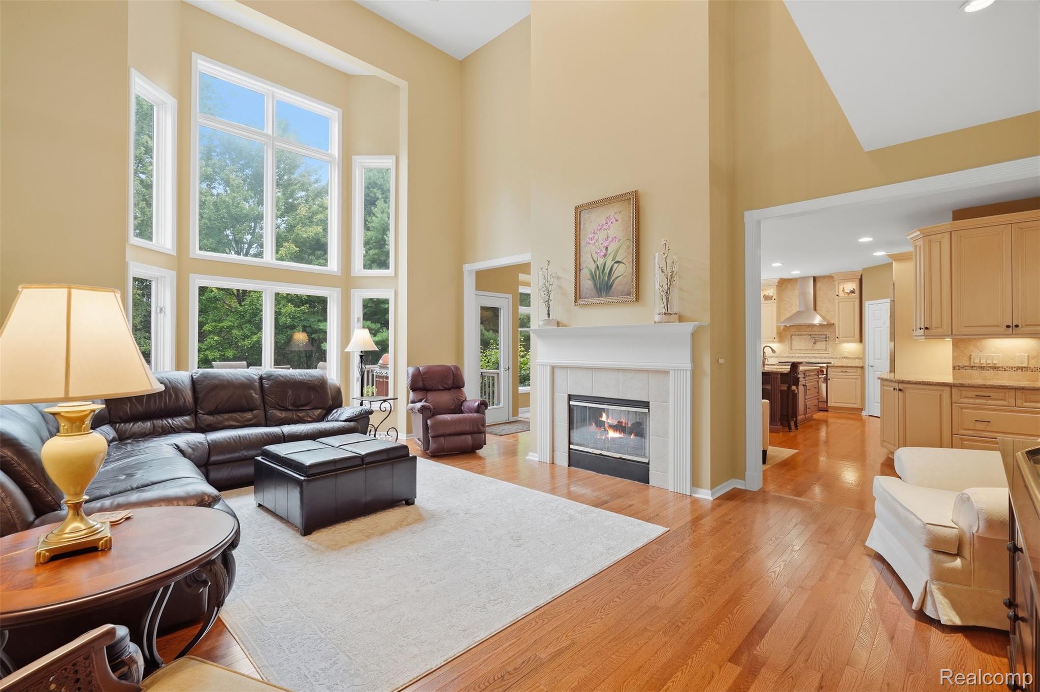 Living room with tall windows, a fireplace, and an open connection to the kitchen.