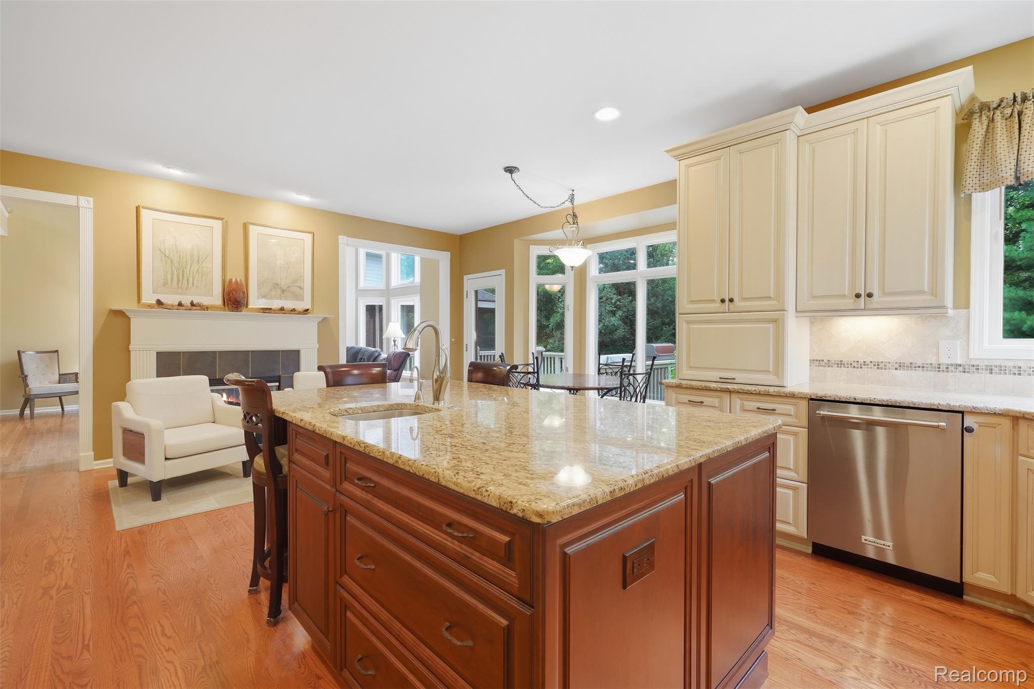 Kitchen with a large granite-topped wood island, cream cabinets, and windows overlooking greenery.