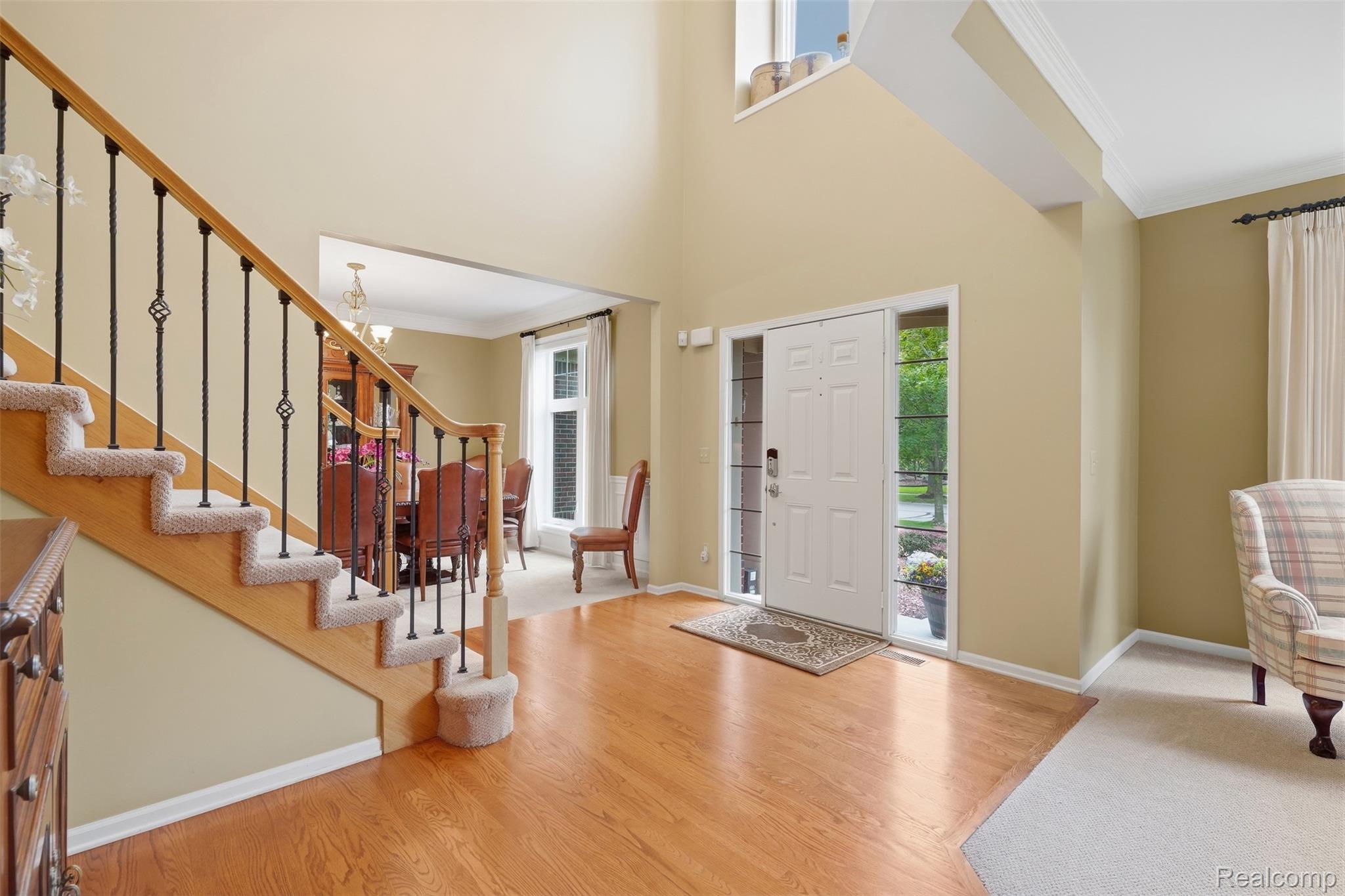 Furnished entry foyer with a carpeted staircase, hardwood floors, and a front door with sidelights.