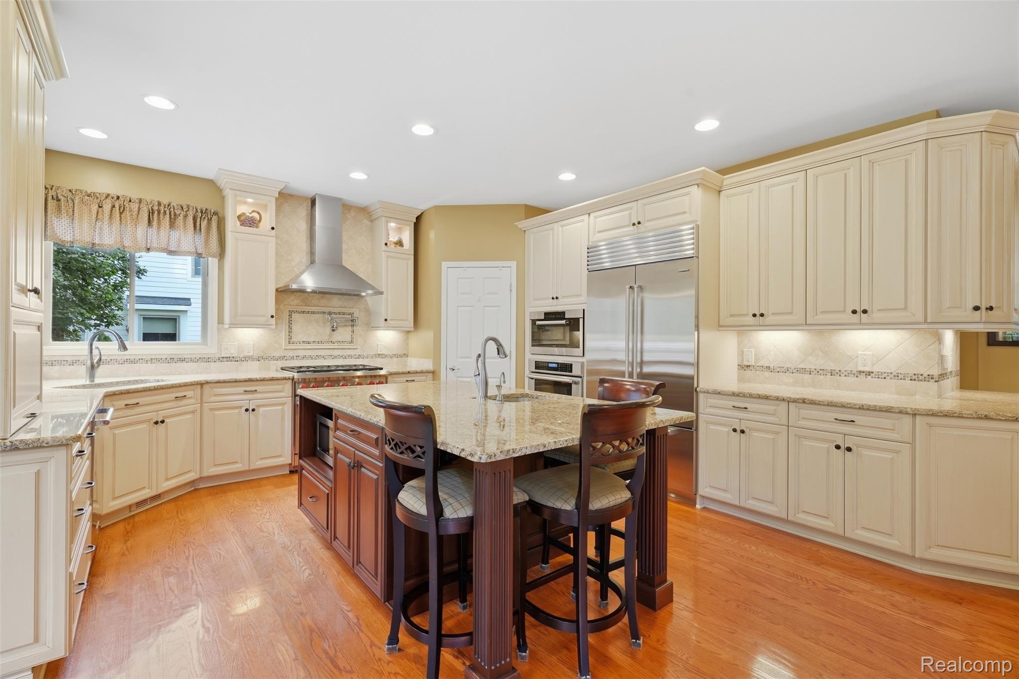 Kitchen with cream cabinets, stainless steel appliances, and a granite island with seating.