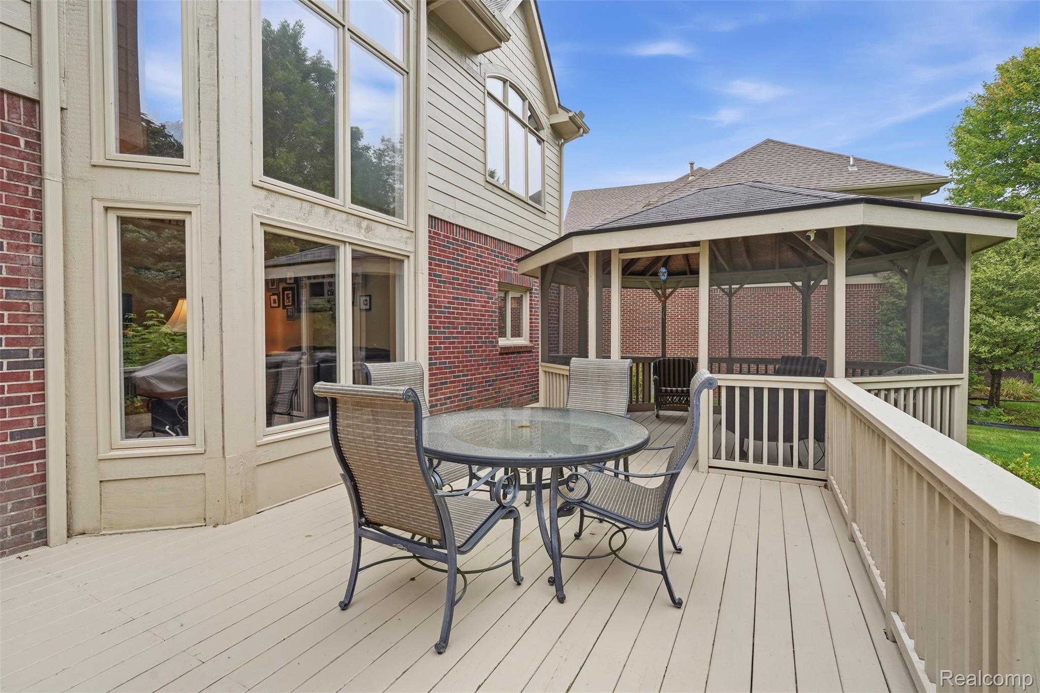 Backyard deck with glass-top dining set and a large covered gazebo.