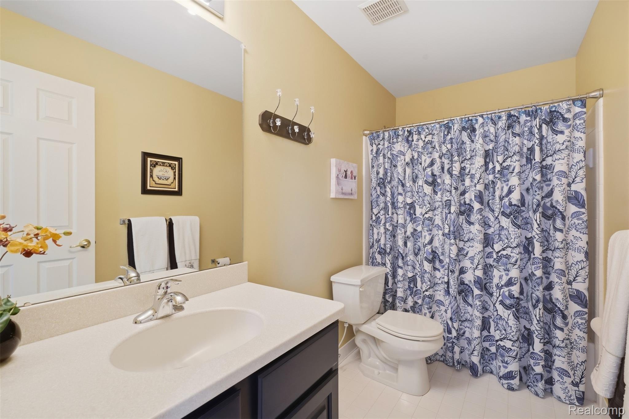 Bathroom with a dark vanity, wide sink counter, and blue-and-white floral shower curtain.