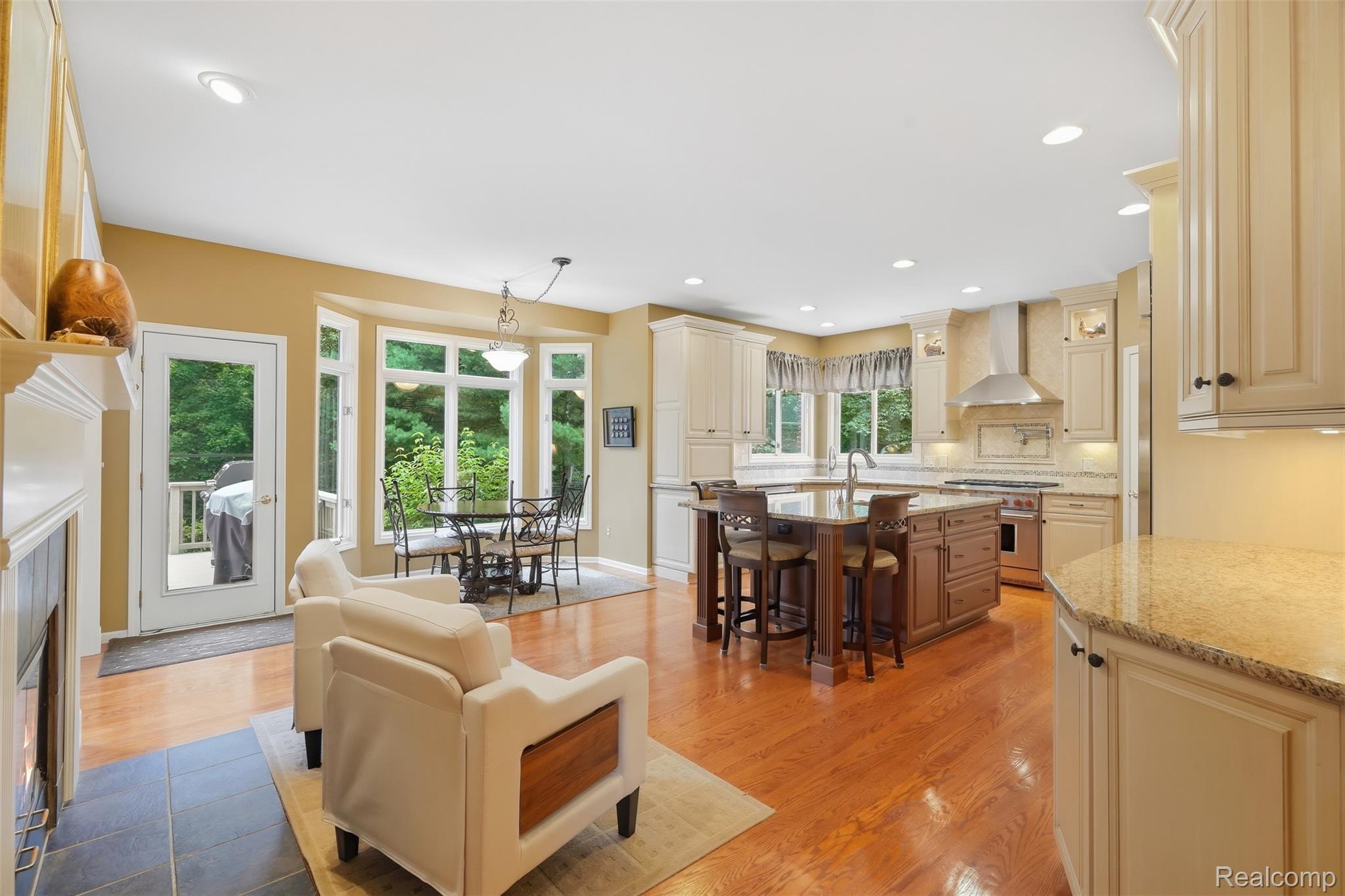 Kitchen with a large wood island, cream cabinetry, hardwood floors, and a dining area by the windows.