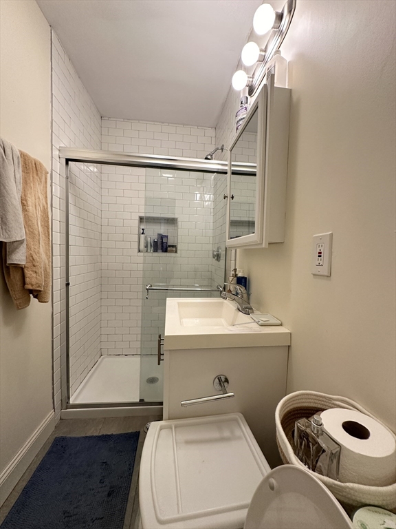 Bathroom with a glass shower, white subway tile, vanity, and dark blue bath mat.