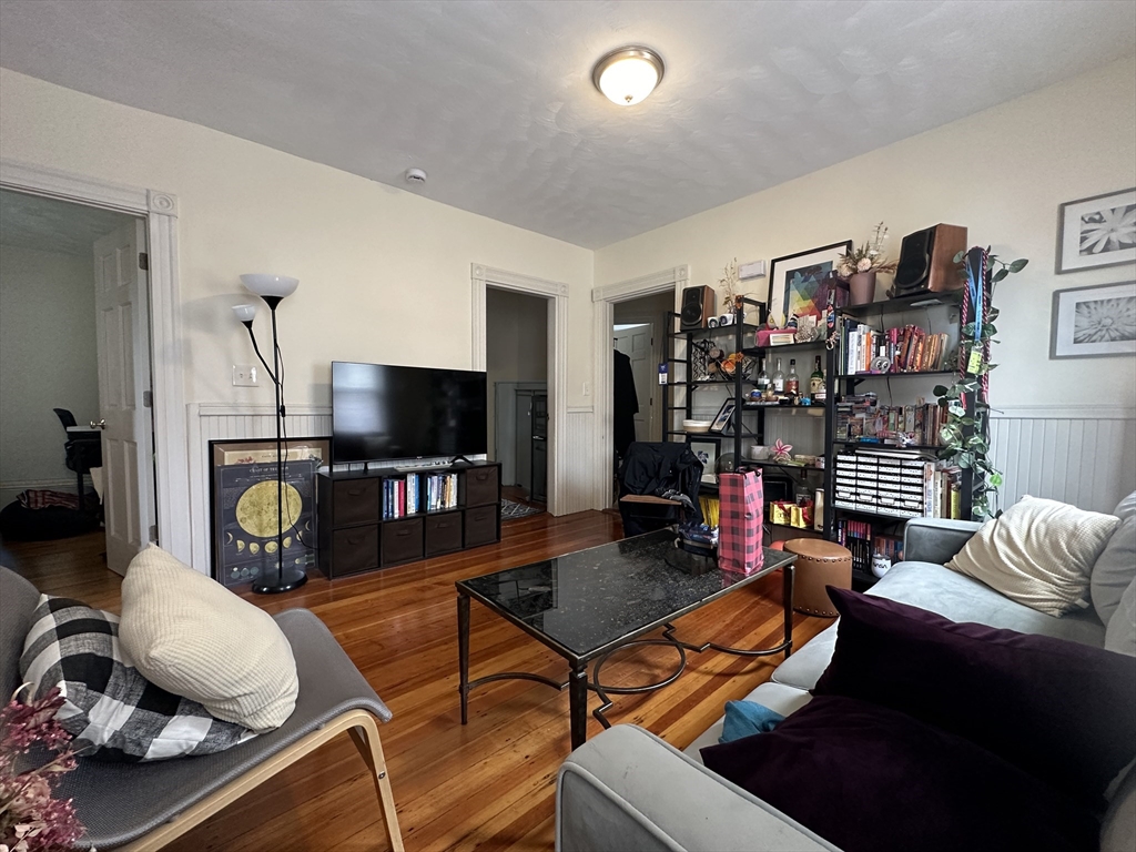 Living room with polished hardwood floors, gray sofas, and a wall of bookshelves.