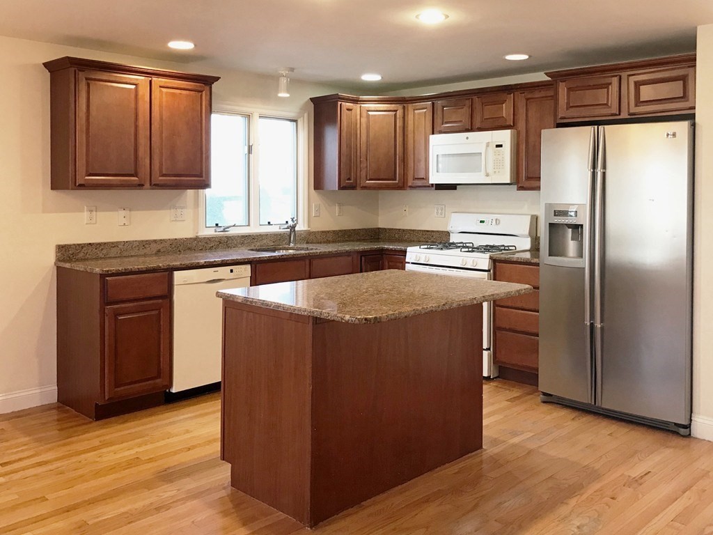 Kitchen with dark wood cabinets, granite countertops, and a central island.
