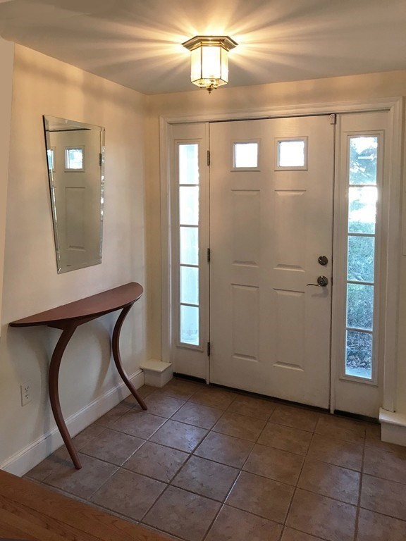 Front entry foyer with a double door, glass sidelights, tiled floor, and console table.