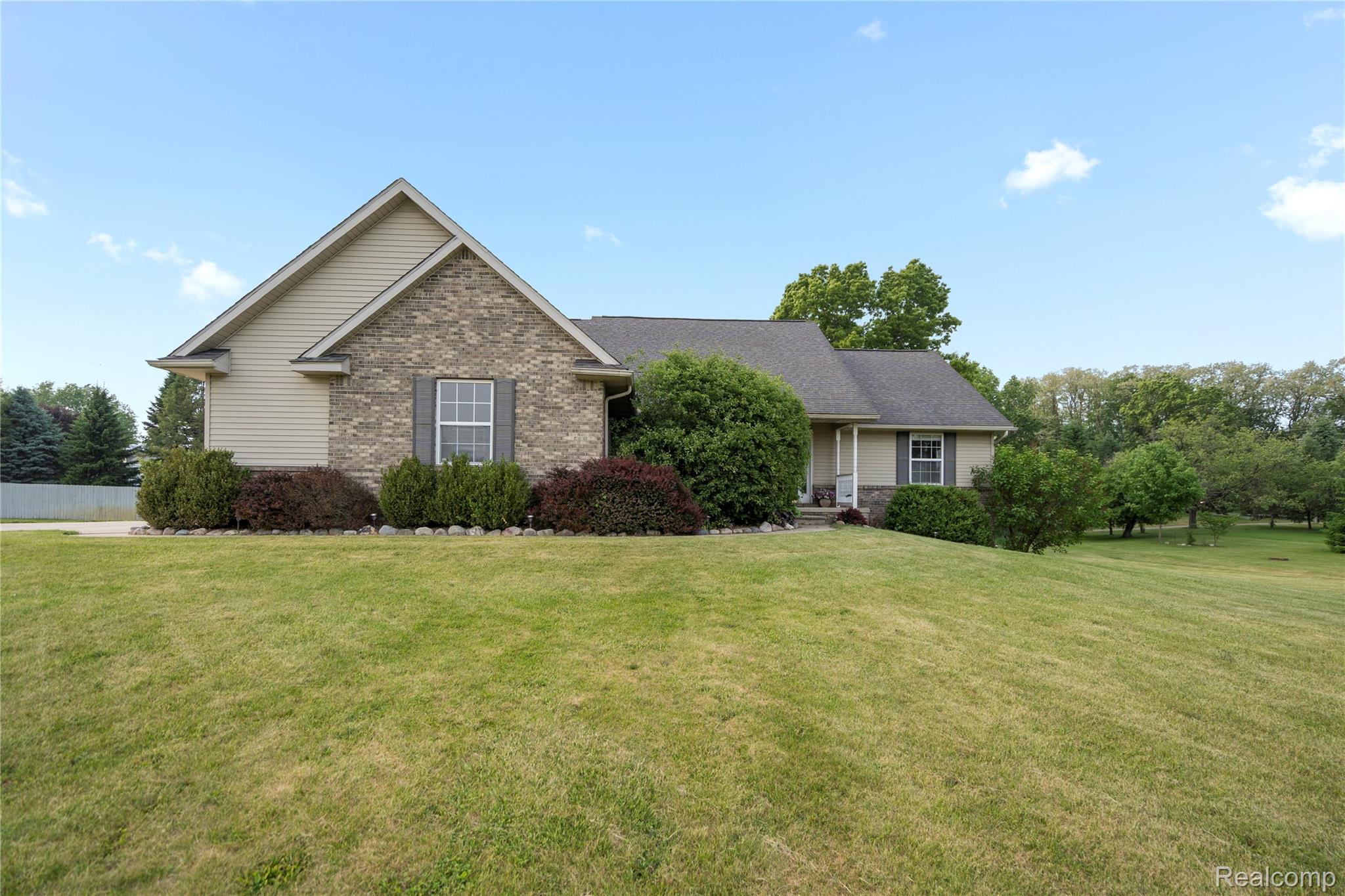 Single-story home with brick accents, landscaped shrubs, and a broad lawn.