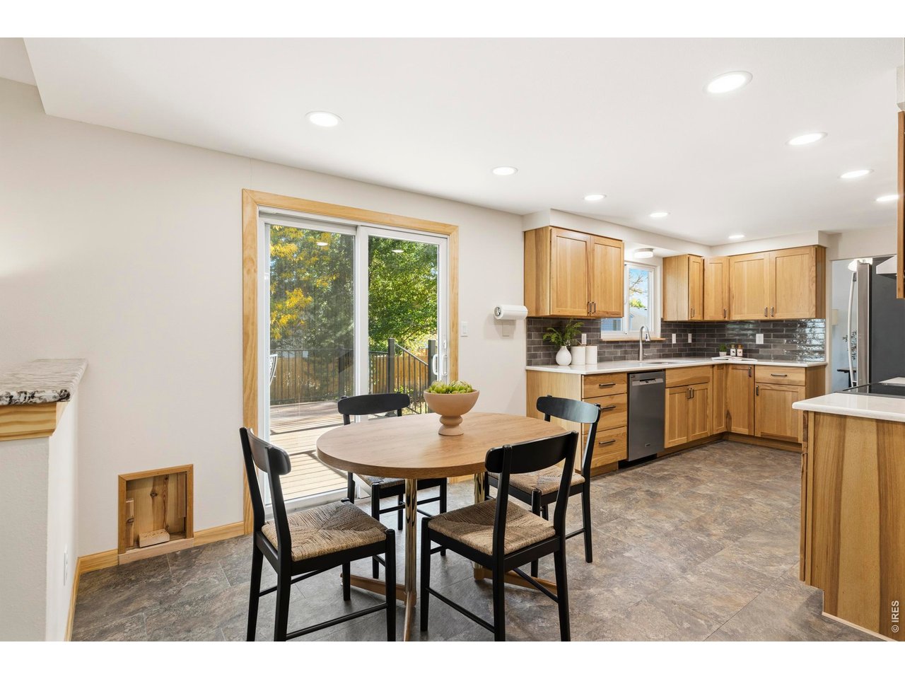 Kitchen and dining area with light wood cabinets, a round table, and sliding doors to a deck.