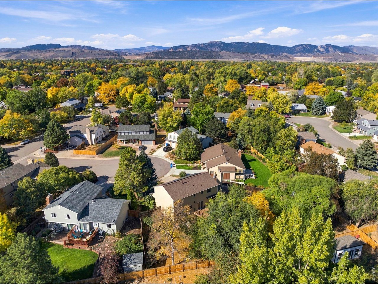 Aerial view of homes among autumn trees, with mountain foothills on the horizon.