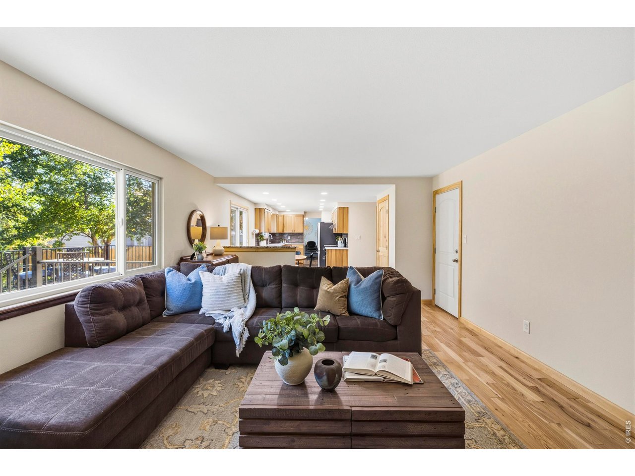 Living room with a dark sectional, wood coffee table, and large windows overlooking trees.