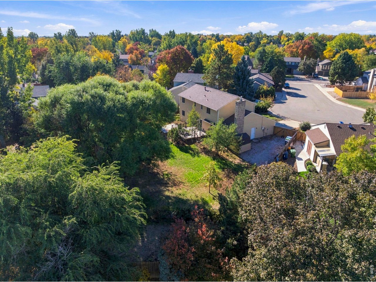 Aerial view of a home and deep backyard surrounded by dense trees and autumn-colored foliage.