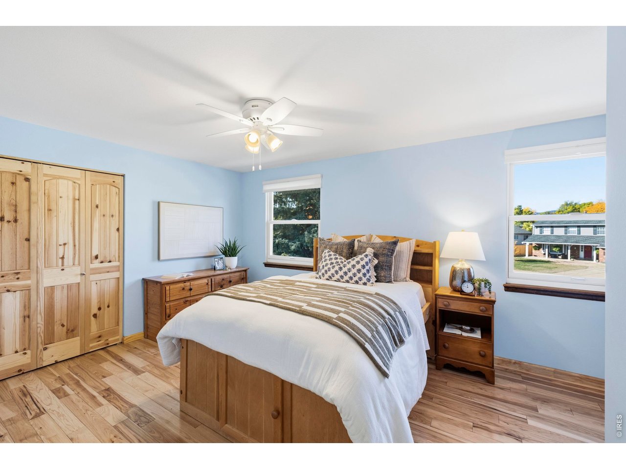 Bedroom with a wooden bed, matching pine wardrobe, and pale blue walls.
