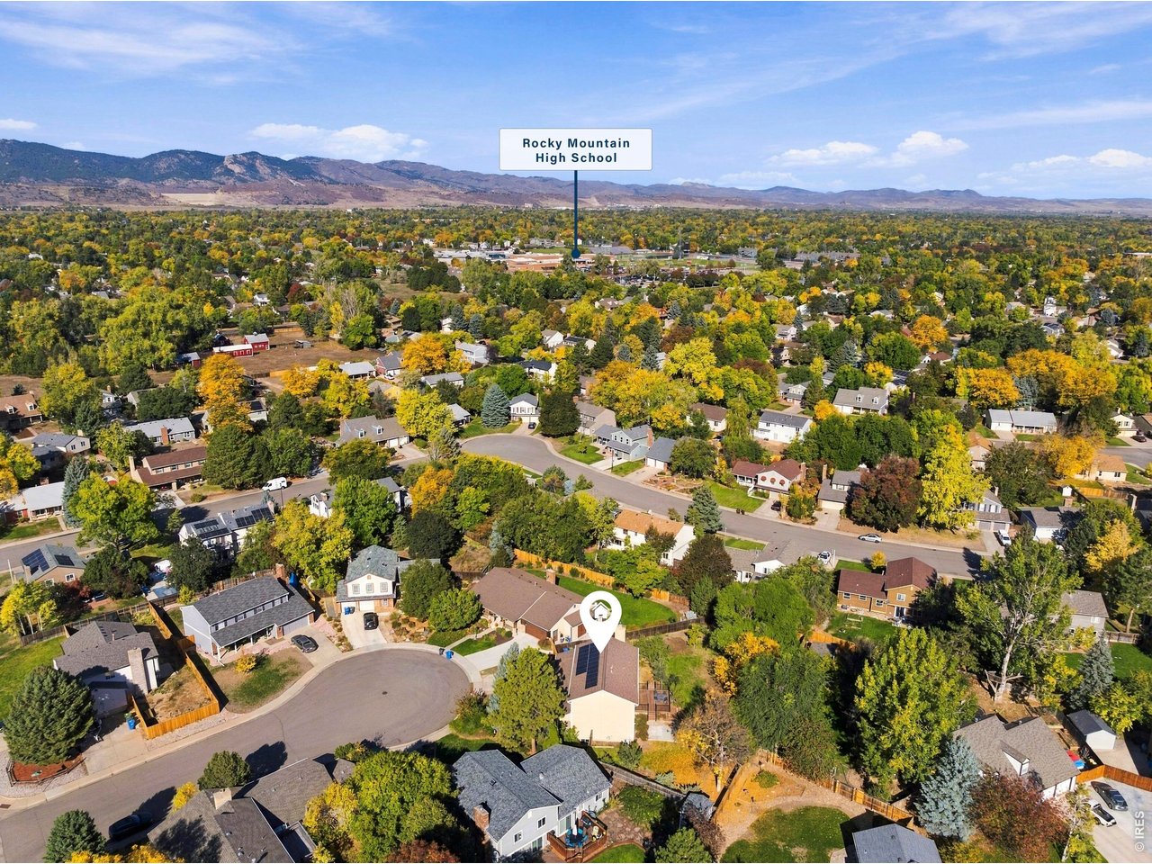 Aerial neighborhood view with the marked home, Rocky Mountain High School, and mountains in the distance.