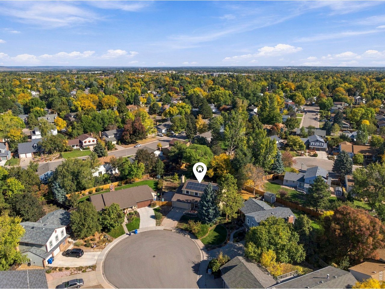 Aerial view of a tree-lined neighborhood, with a pin marking a home with rooftop solar panels.