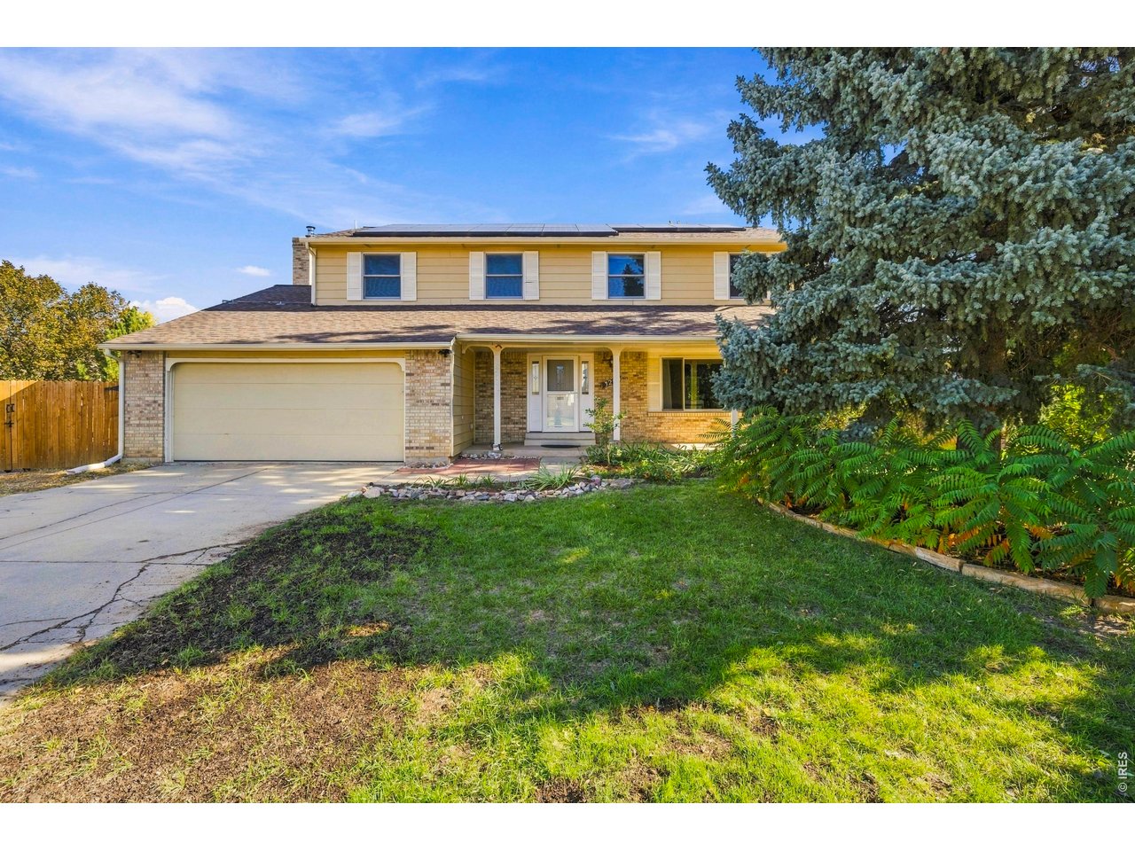 Two-story home with rooftop solar panels, an attached garage, and a covered front porch.