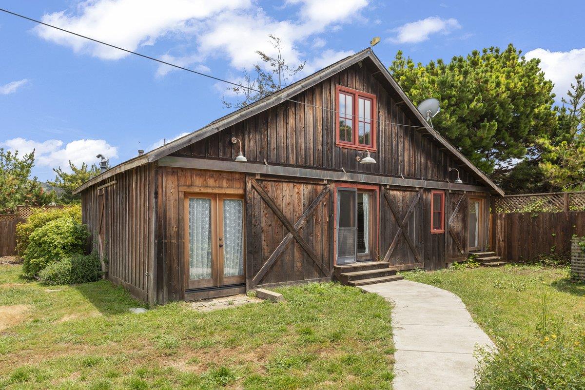 Rustic dark-wood home with red-trimmed windows and a curved walkway through the front yard.