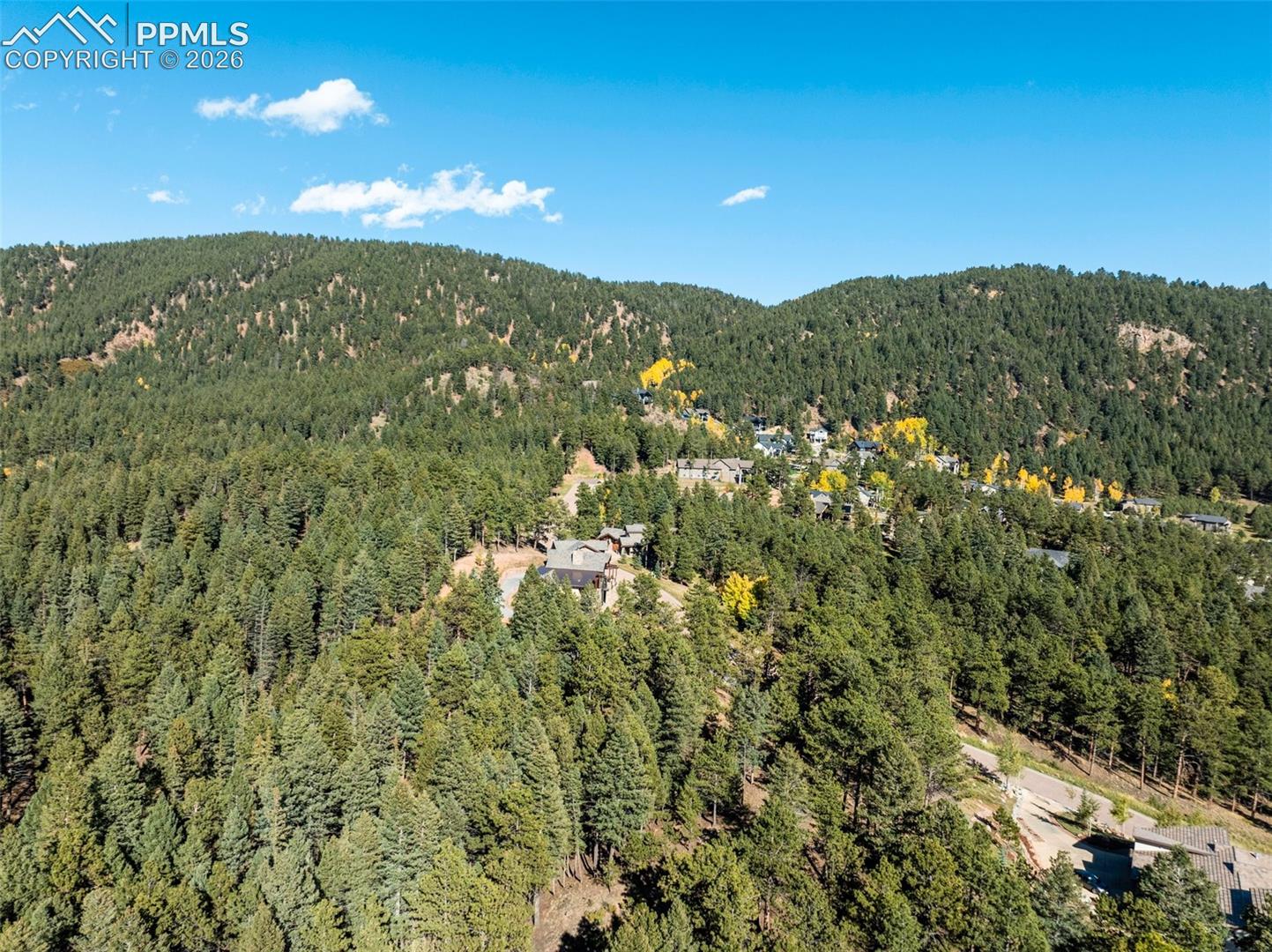 Aerial view of a wooded mountain neighborhood with scattered homes and golden aspens.