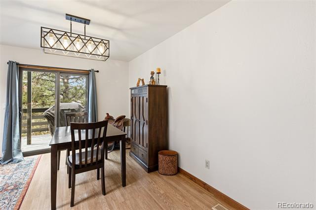 Dining room with dark wood furniture beside sliding glass doors overlooking a tree-lined deck.