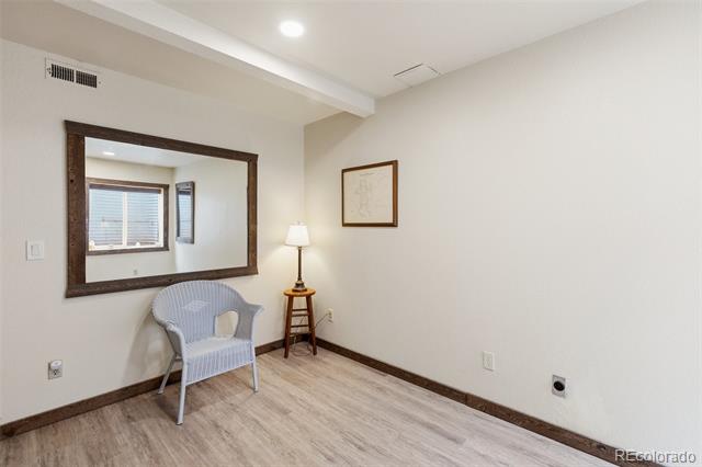 Sparse room with a wicker chair, floor lamp, dark trim, and a large mirror reflecting a window.