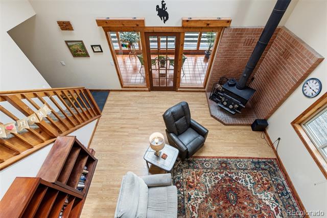 Living room with a brick fireplace, black wood stove, patterned rug, and wood-framed glass doors.