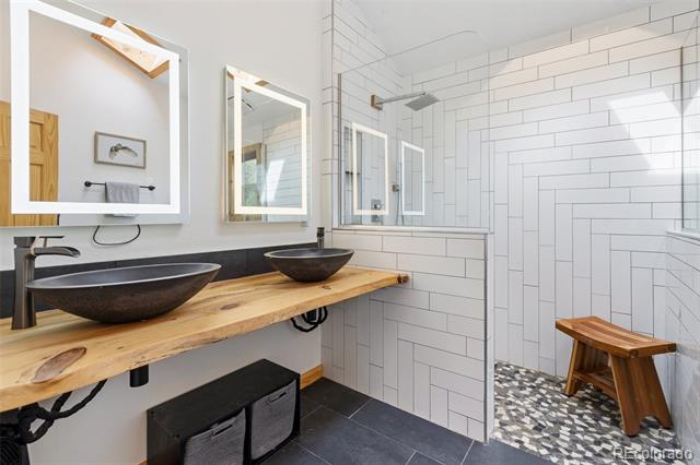 Bathroom with a live-edge wood vanity, two vessel sinks, and a glass-enclosed tiled shower.