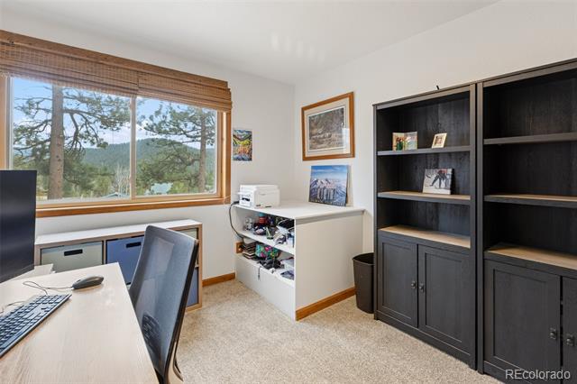 Home office with dark built-in cabinets and a large window overlooking trees and hills.