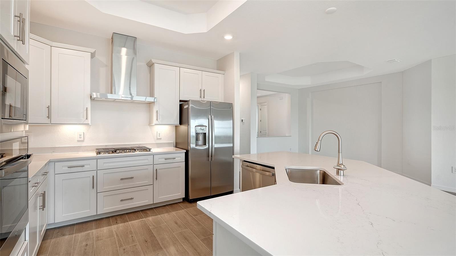 Modern kitchen with white cabinets, stainless appliances, and a large island with sink.