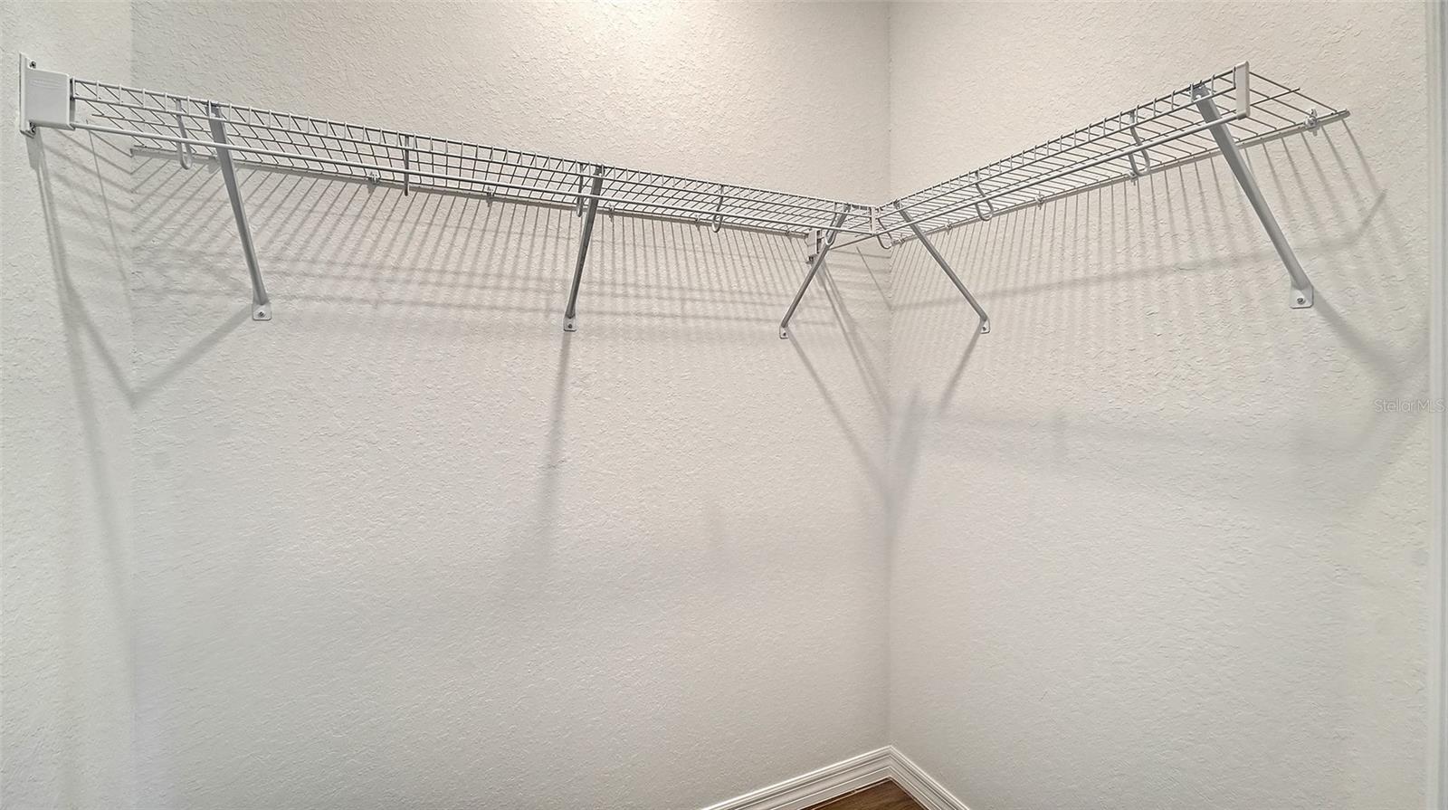Empty walk-in closet with white wire shelving along two walls.