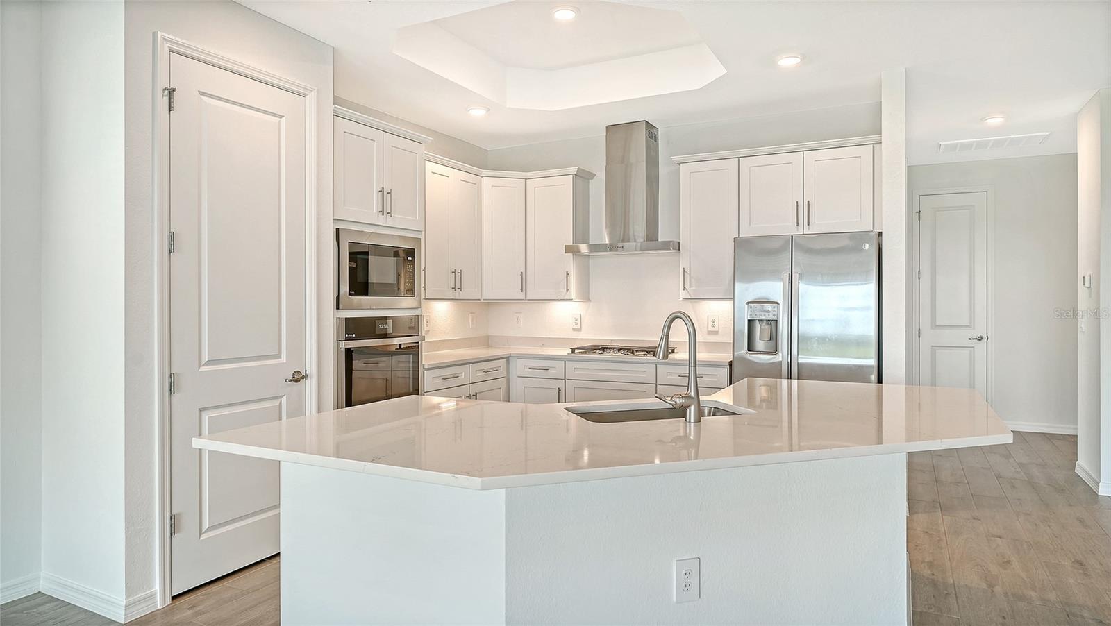 Kitchen with white cabinetry, a large quartz island, and stainless steel appliances.