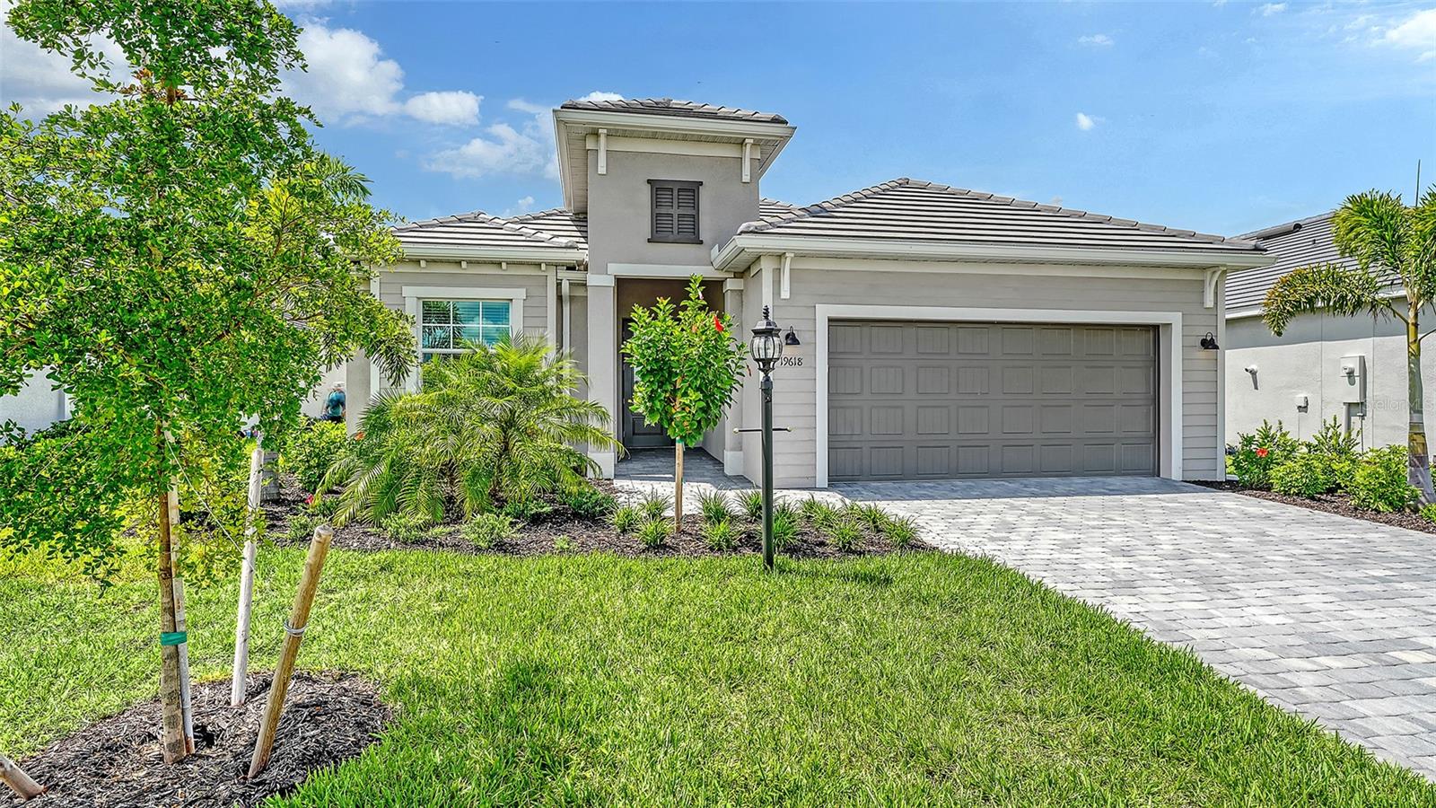 Gray single-story home with a wide garage, paved driveway, and landscaped front lawn.