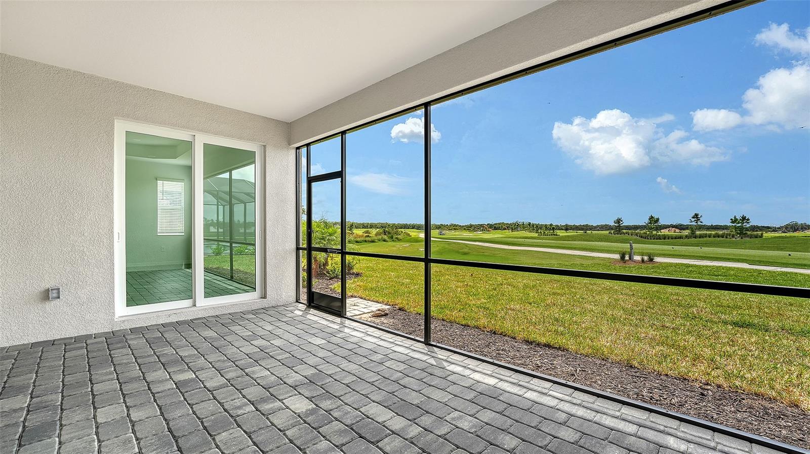 Screened paver lanai overlooking a green golf course.