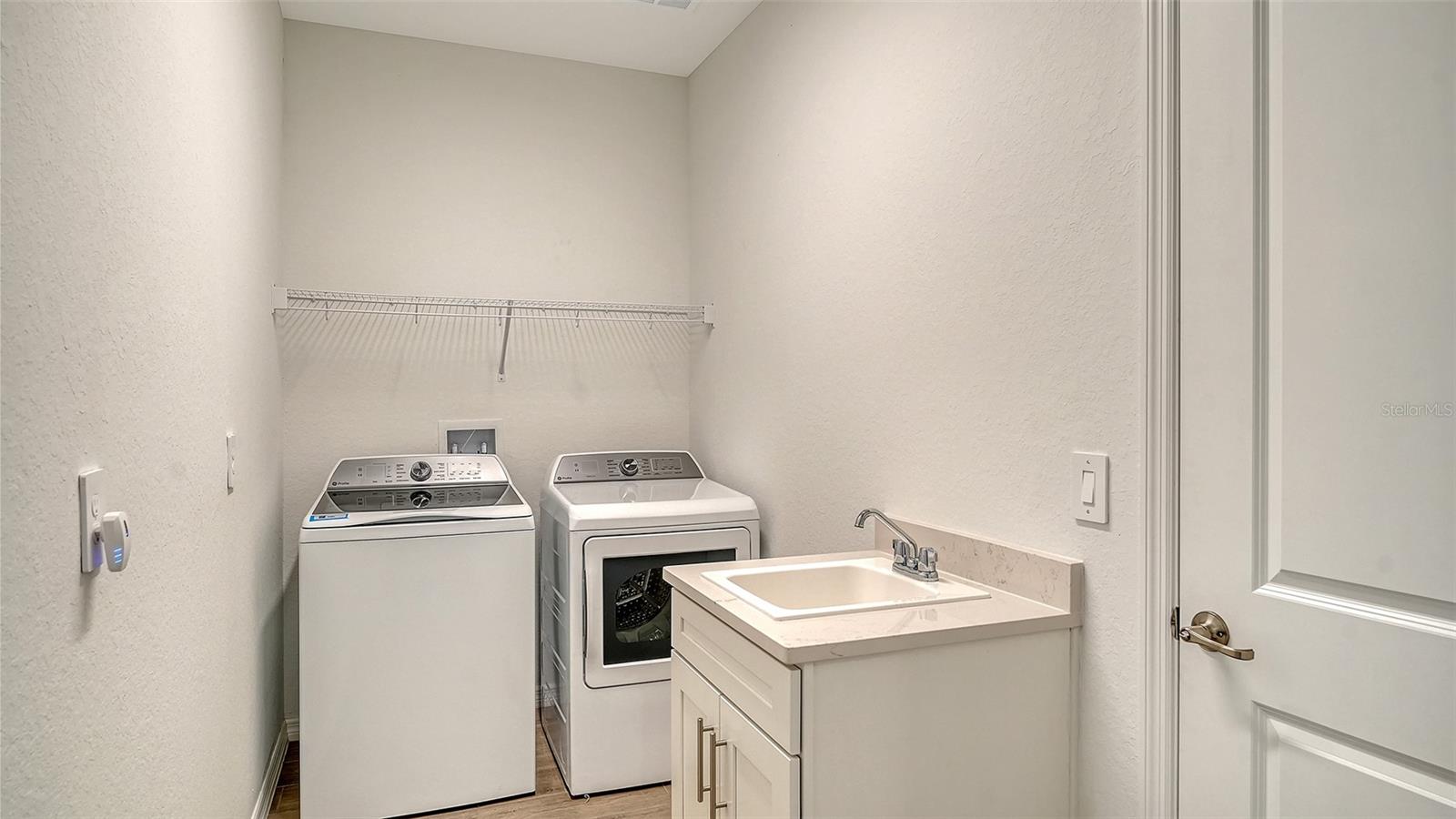 Laundry room with washer, dryer, and a utility sink with white cabinet vanity.